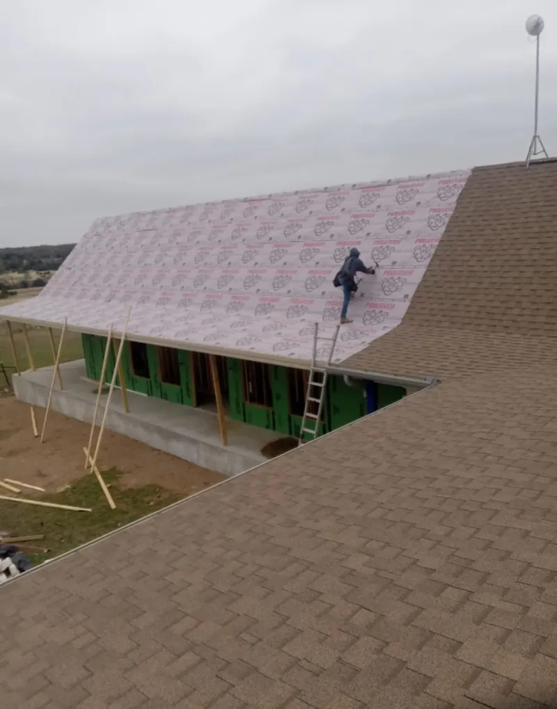 Worker preparing underlayment for a metal roof installation in Gateway